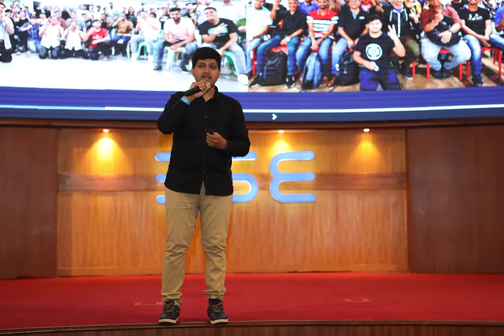 Ali Mustufa Shaikh giving the Google Cloud Community Day Mumbai keynote, with community photos behind him.