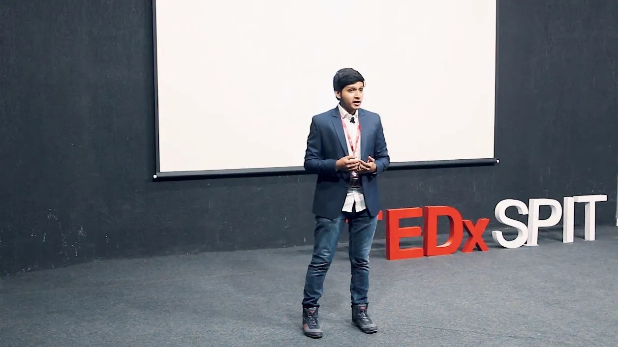 Ali Mustufa Shaikh speaking on stage beside the TEDxSPIT letters.